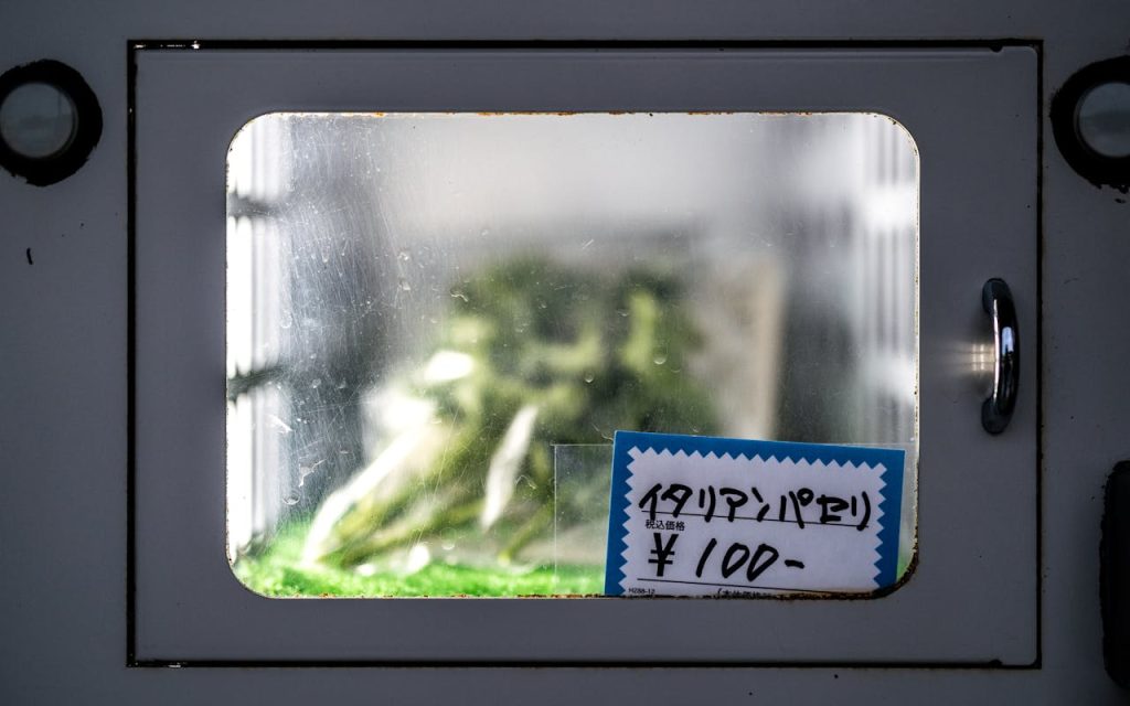 A vending machine window displaying Italian parsley priced at 100 yen in Japan.
